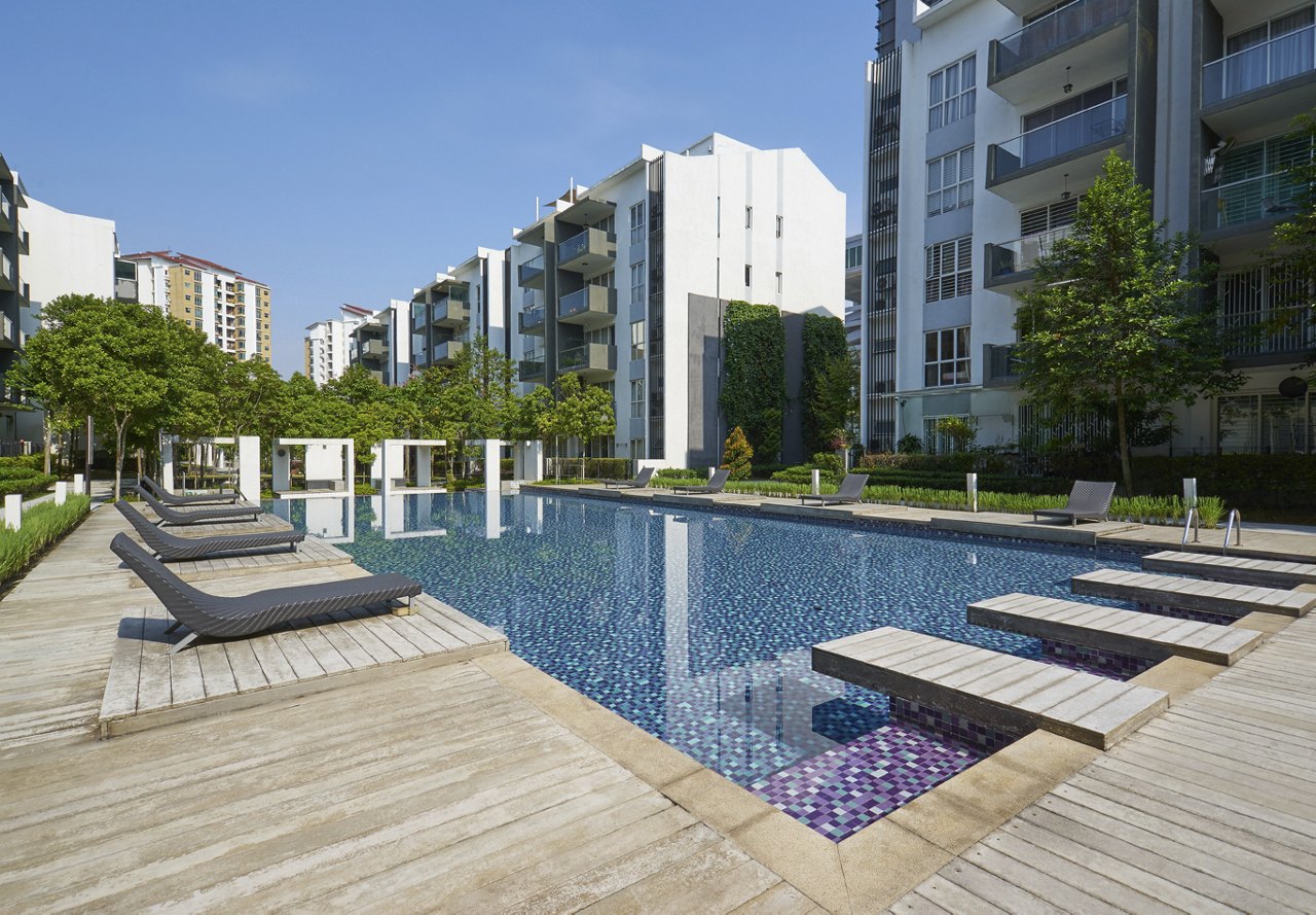 A serene apartment pool surrounded by lounge chairs, set against a backdrop of modern buildings, with wood plank flooring adding a stylish touch.