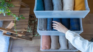 person storing seasonal clothing in plastic bins
