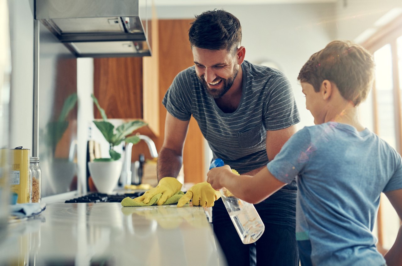 Shot of a father and son cleaning the kitchen counter together at home.