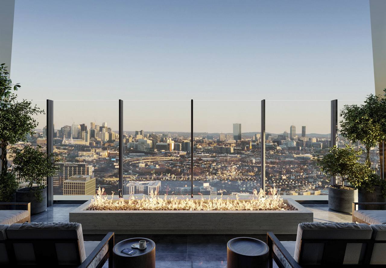 A rooftop fire pit with seating overlooking a panoramic cityscape during sunset.