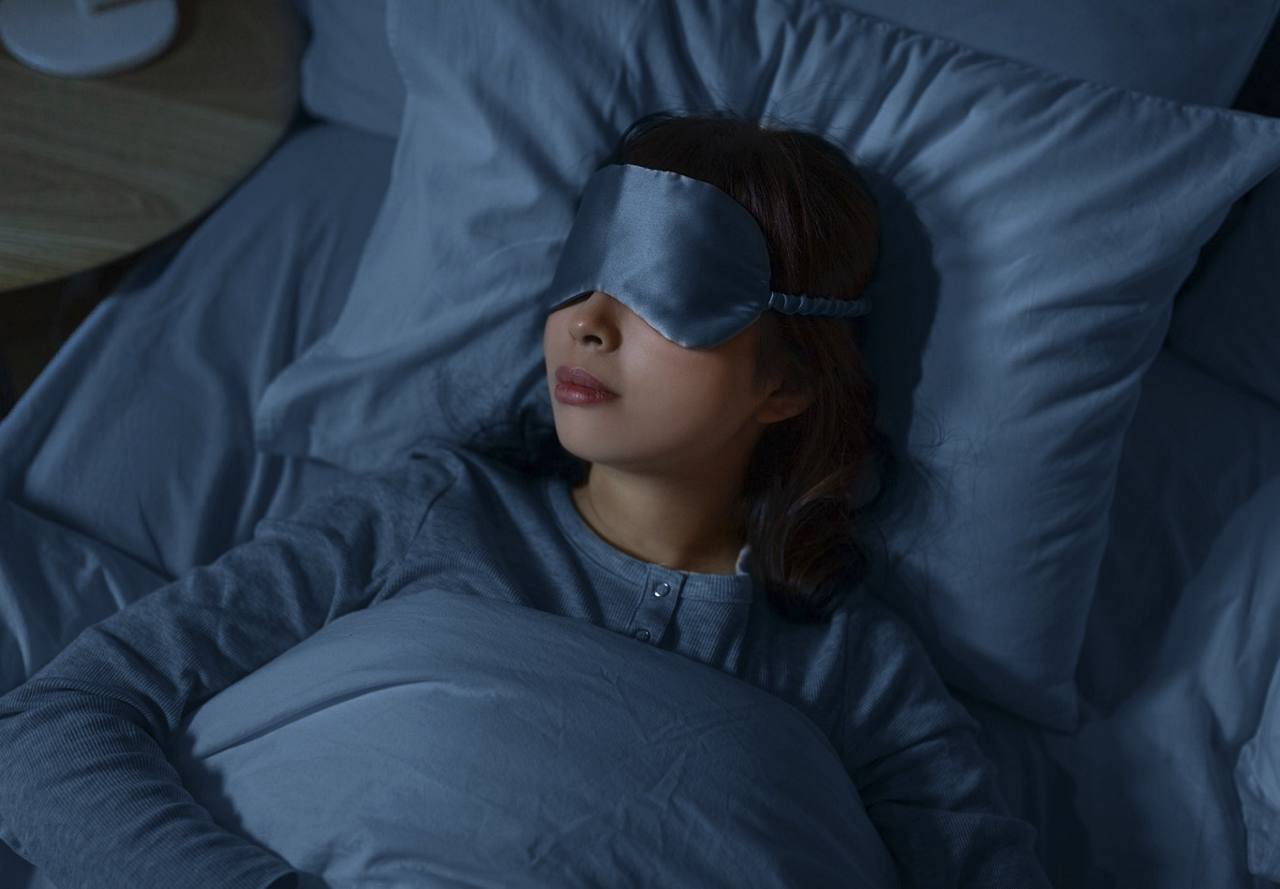 woman wearing sleep mask lying in bed