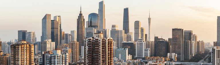 A panoramic view of a dense city skyline at sunset, showcasing a mix of modern high-rises and older residential buildings