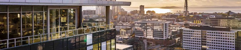 Dusk skyline featuring 'ASCENT' residential building with illuminated windows, flanked by high-rise buildings.