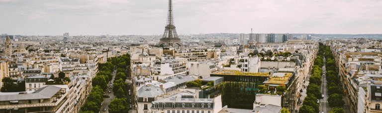 Captivating view of a classic French streetscape, featuring charming buildings with traditional architecture, balconies adorned with flowers, and a cobblestone street, all bathed in the warm, golden glow of streetlights.