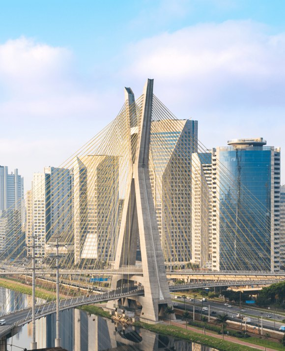 The Octavio Frias de Oliveira Bridge, a cable-stayed bridge with two curved decks, in São Paulo, Brazil, against a blue sky.