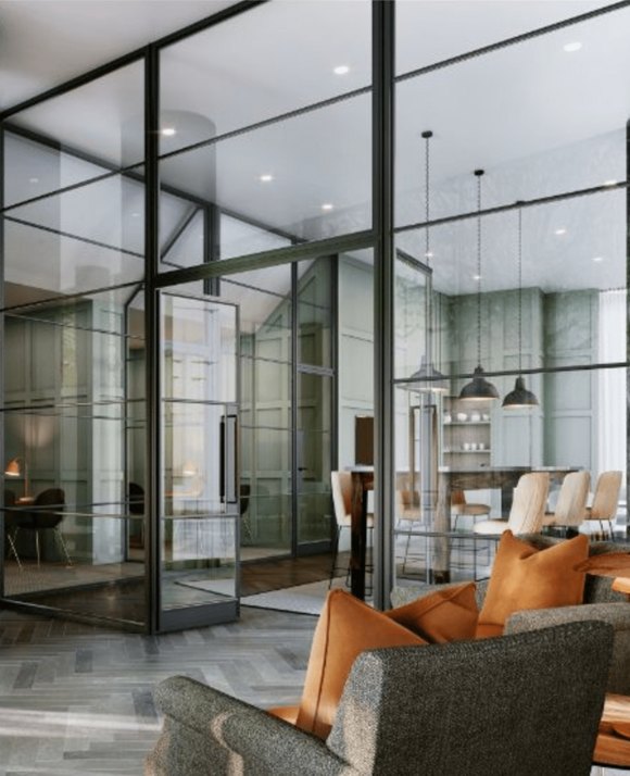 Elegant interior view of an office space with glass partitions, showcasing a modern meeting room and comfortable seating area with plush sofas and orange pillows.