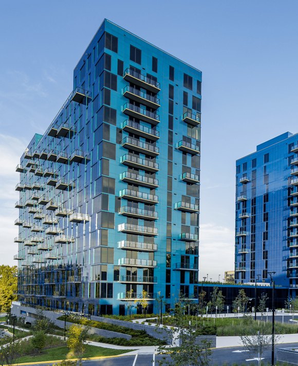 Modern high-rise buildings with blue and turquoise reflective glass exteriors against a clear sky.