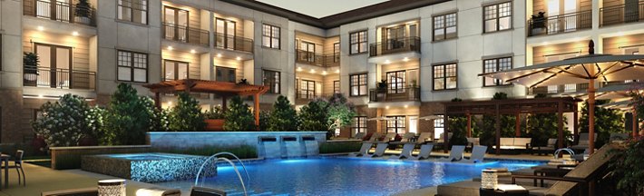 Evening view of a luxurious apartment complex with illuminated balconies overlooking a serene pool area with lounge chairs and a covered seating area.