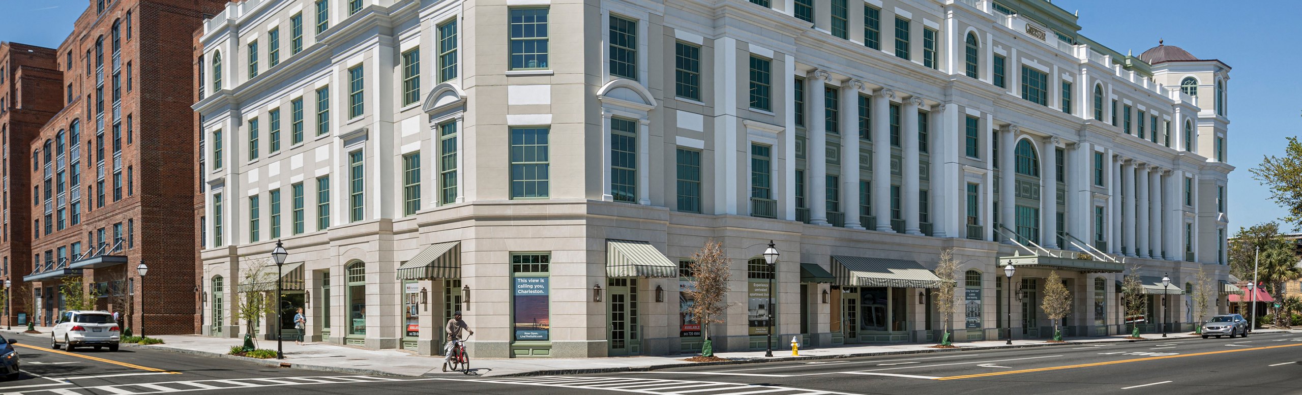 Classic and modern architecture blend in this streetscape featuring a new, elegant white building with prominent columns beside a traditional red brick structure.