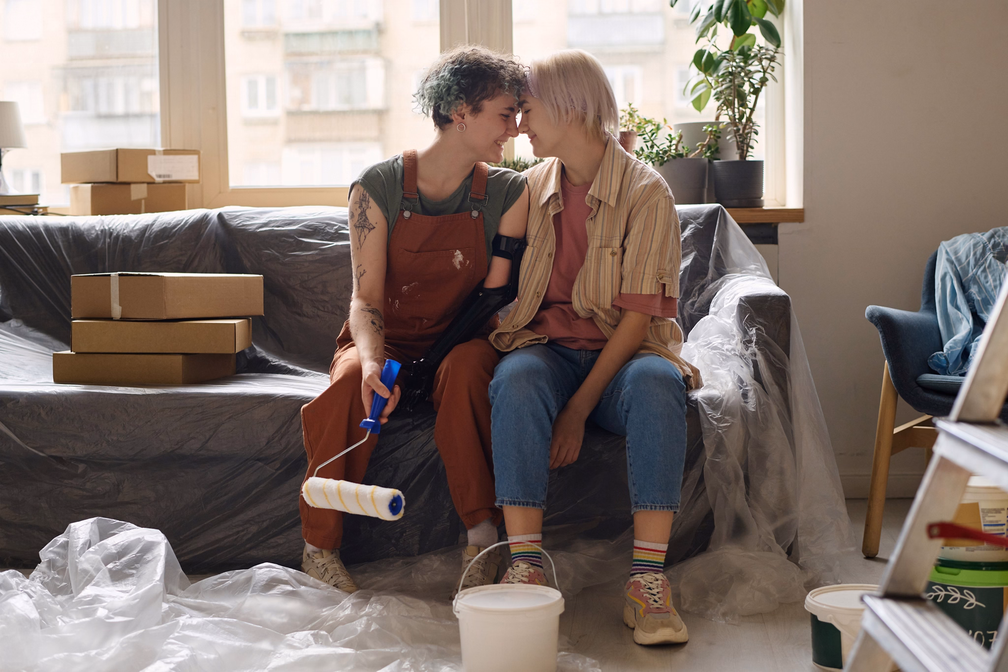 Lesbian couple making repair together in their new apartment, they sitting on sofa and enjoying each other