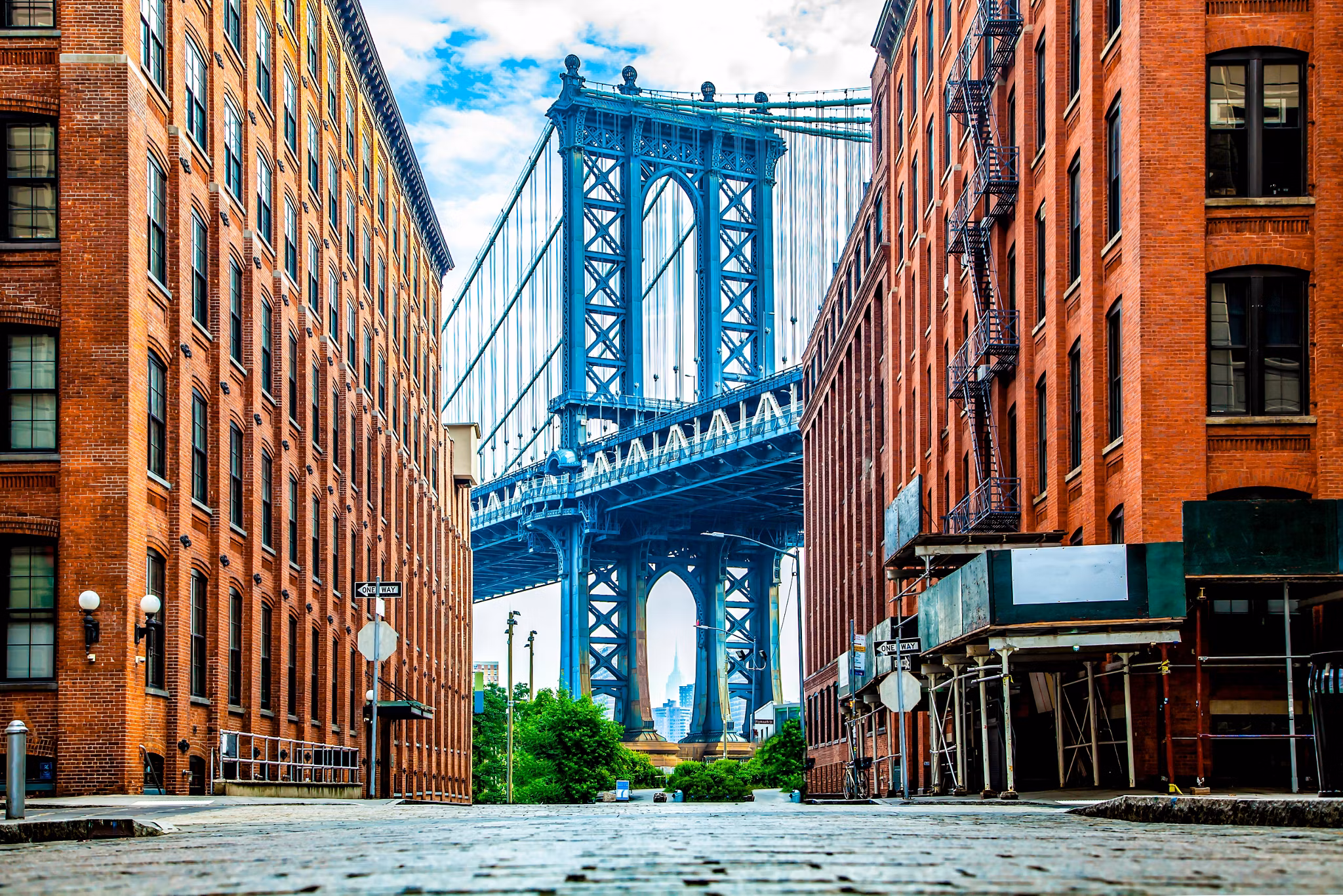 Manhattan Bridge between Manhattan and Brooklyn over East River seen from a narrow alley enclosed by two brick buildings on a sunny day in Washington street in Dumbo, Brooklyn, NYC