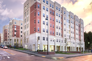 Exterior view of Jewell Hall, a traditional collegiate-style dormitory at the University of Kentucky, showcasing its classic red brick facade, white window frames, and collegiate gothic architectural elements, set against a clear sky.