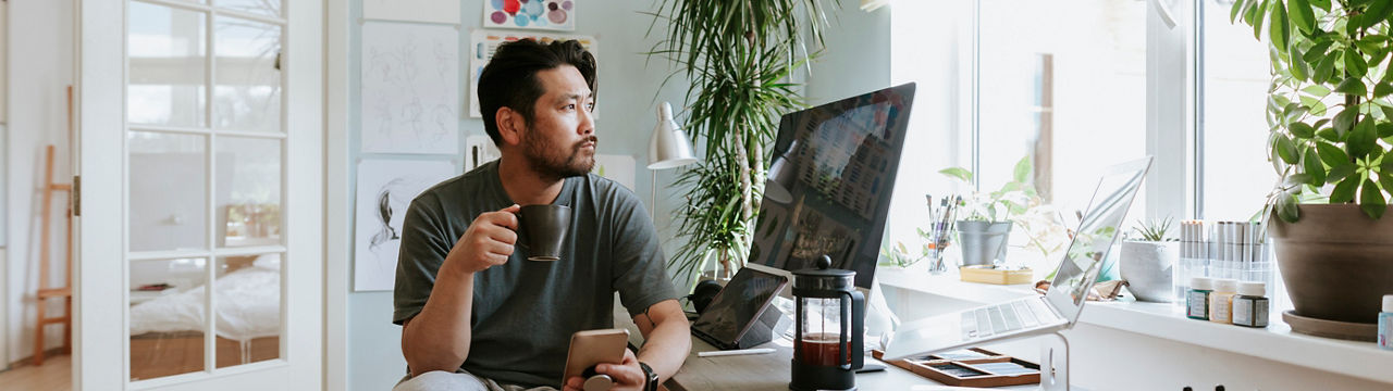 Photo series of Asian digital artist at his home studio taking a coffee break.