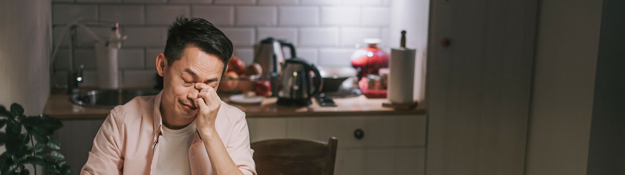 Asian chinese male working late at home dining room emotional stress with his financial bill alone at night