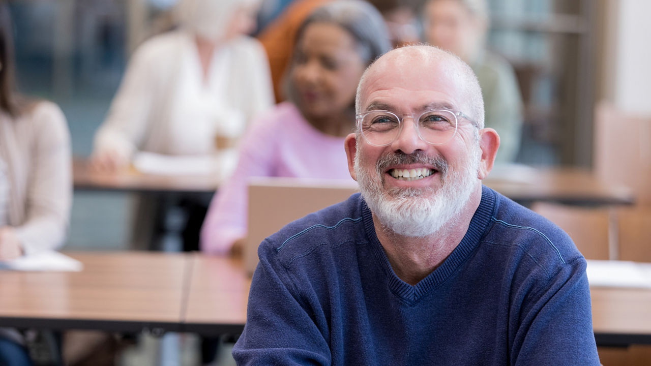 Confident mature male college student smiles during a professor's lecture 