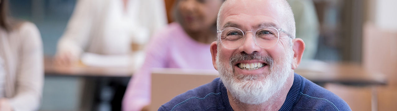 Confident mature male college student smiles during a professor's lecture 