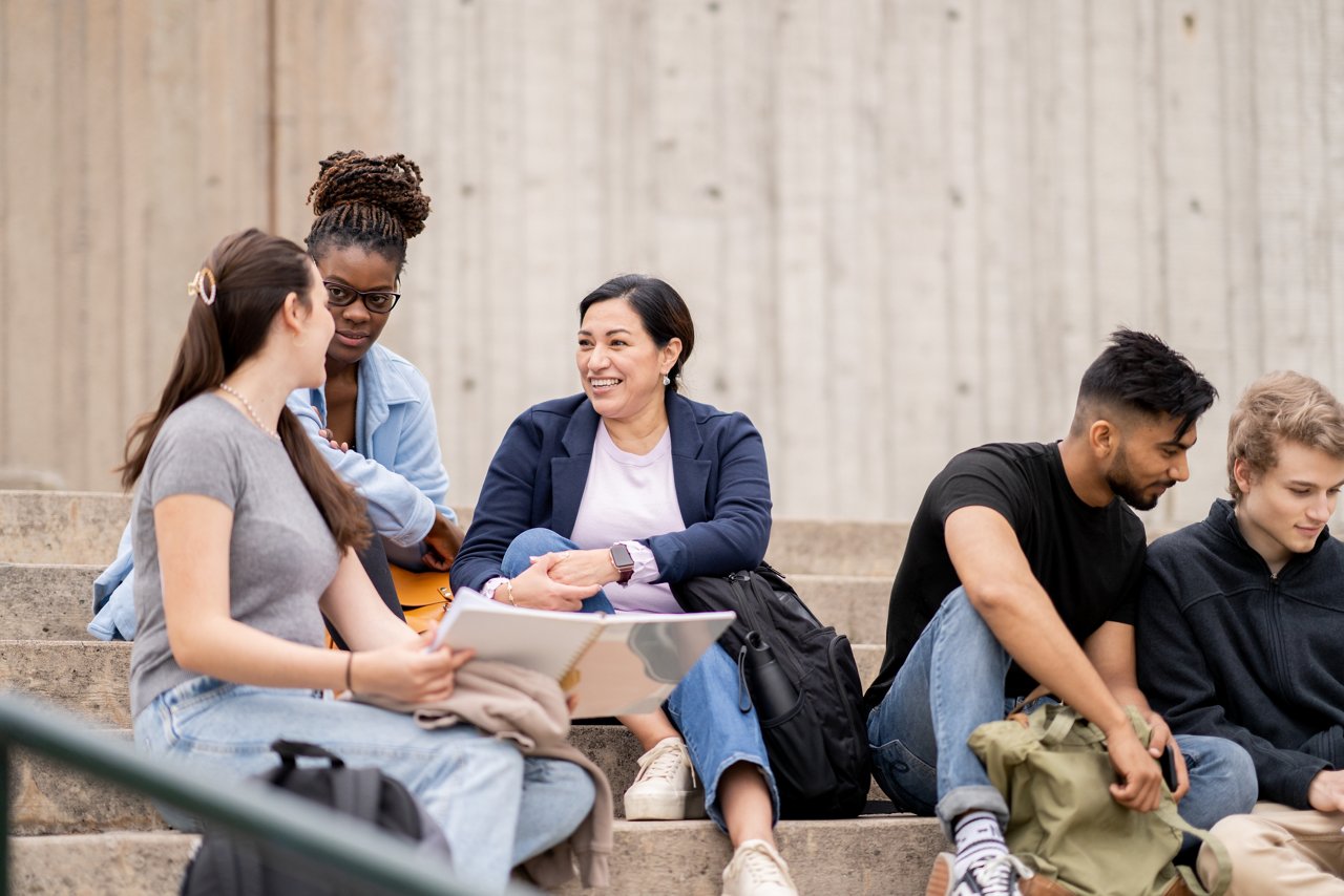 A diverse group of university students review each other's notes while studying for an exam.