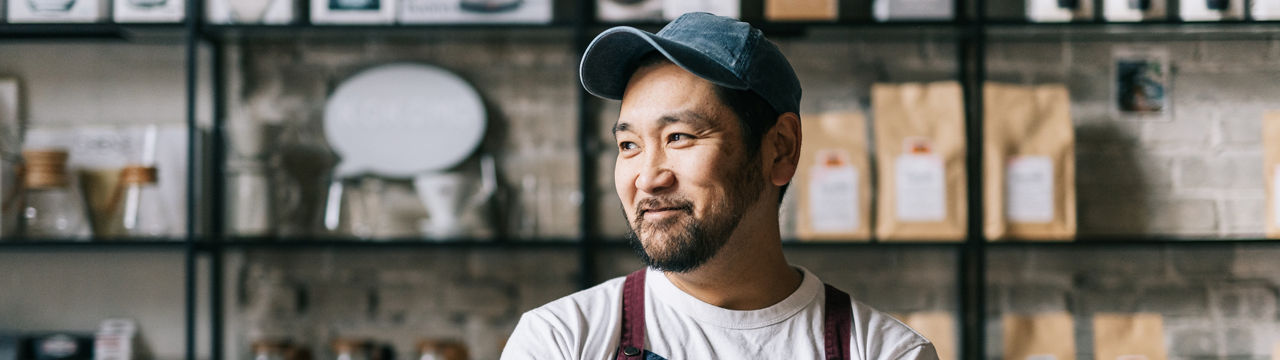 Standing tall and confident, this small business owner expertly operates his coffee roastery shop, producing top-quality beans.