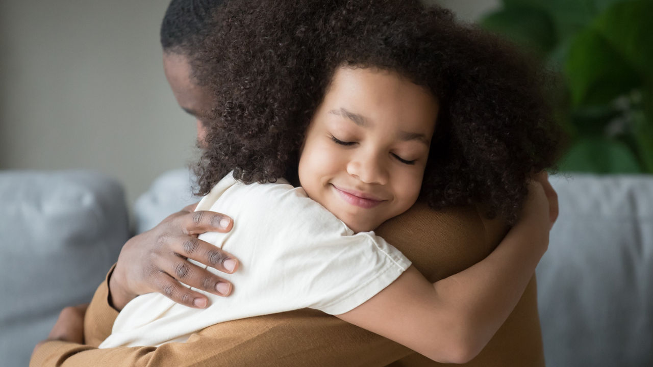 Cute mixed race child daughter embracing black father holding tight feeling love connection affection concept, happy african family dad and little kid girl hugging cuddling bonding at home