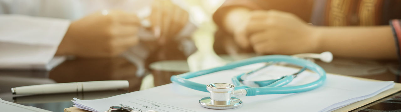 Stethoscope with clipboard and laptop on desk