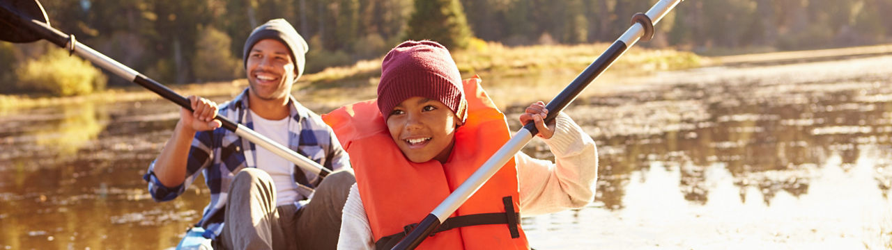 Father and son rowing kayak on lake