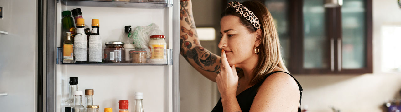 Shot of a young woman searching inside a refrigerator at home