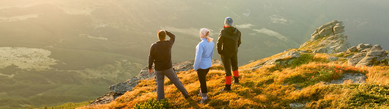 Friends look to the sunset in mountains