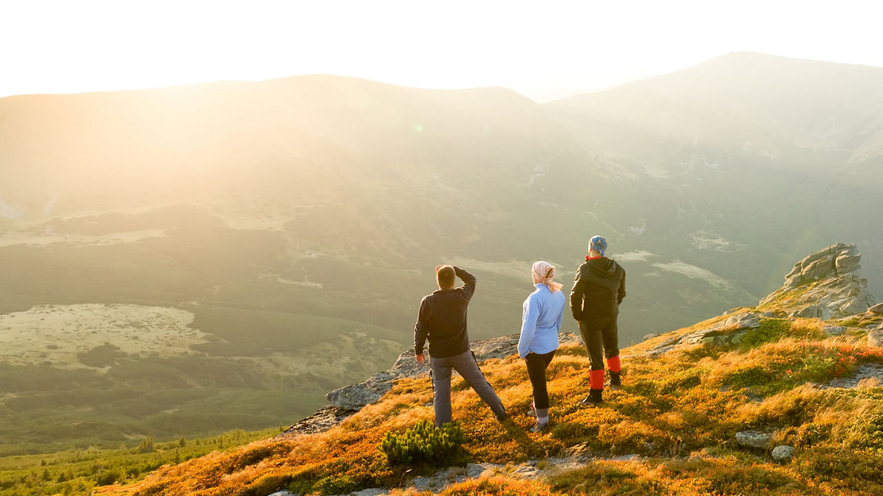 Friends look to the sunset in mountains