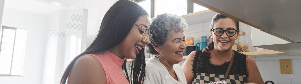 Grandmother, mother and daughter unpacking groceries in the kitchen
