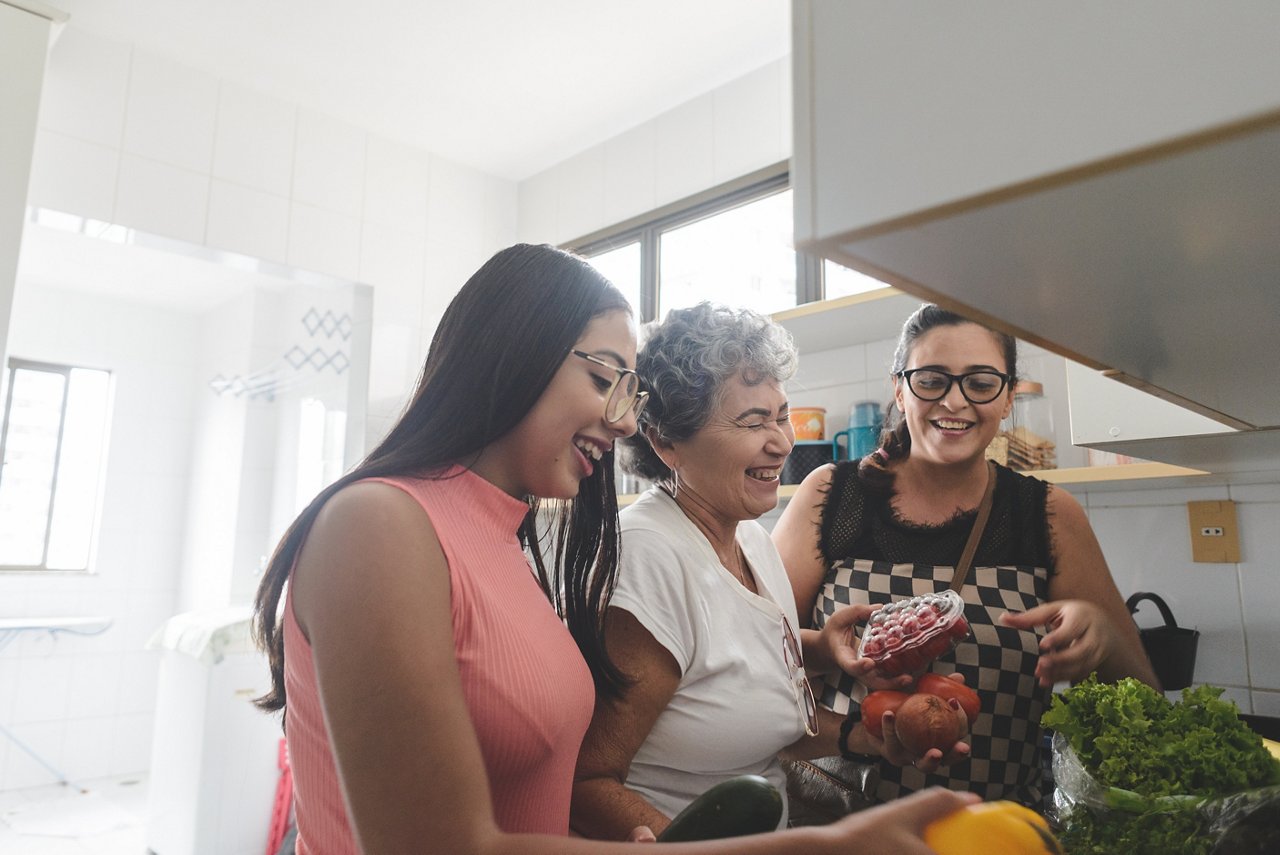 Grandmother, mother and daughter unpacking groceries in the kitchen