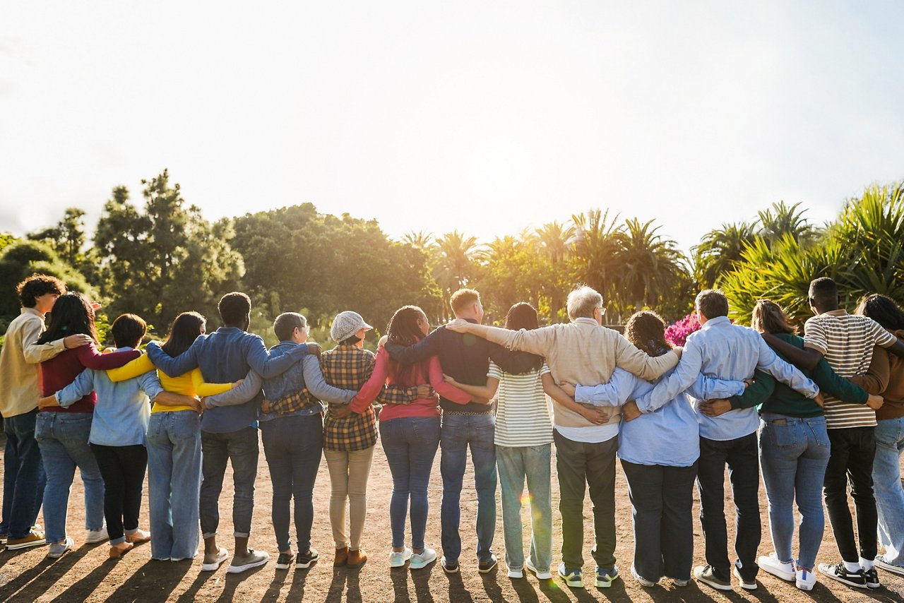 a group of diverse individuals smiling locking shoulders