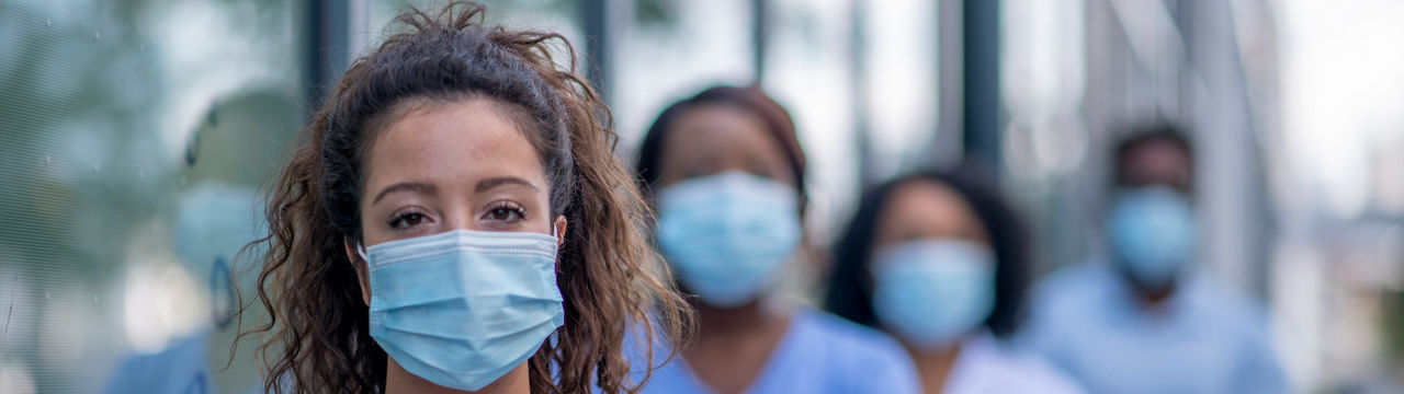 Diverse group of medical professionals outside the hospital wearing protective face masks