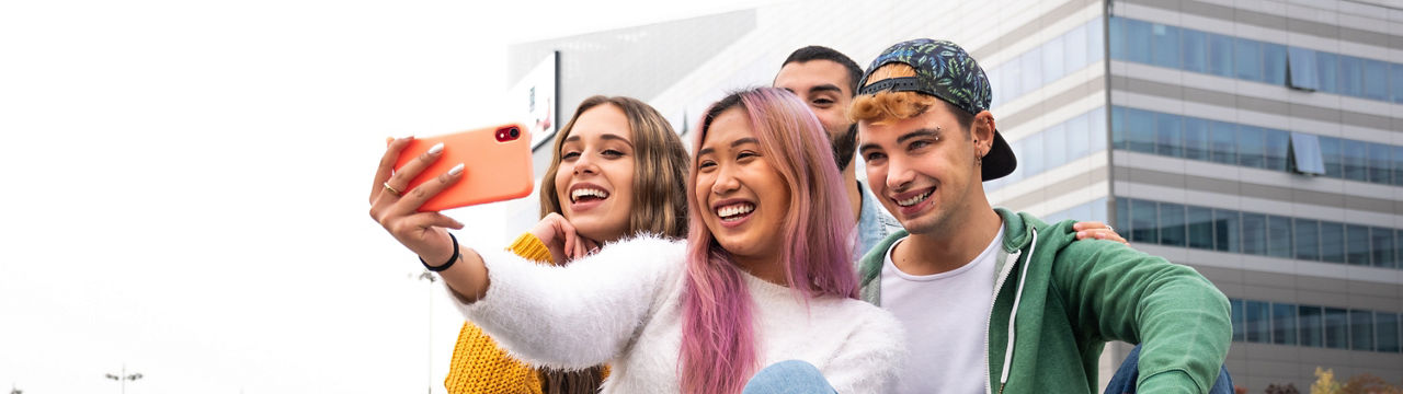 happy group of young skater friends takes a selfie sitting outdoors on a skateboard