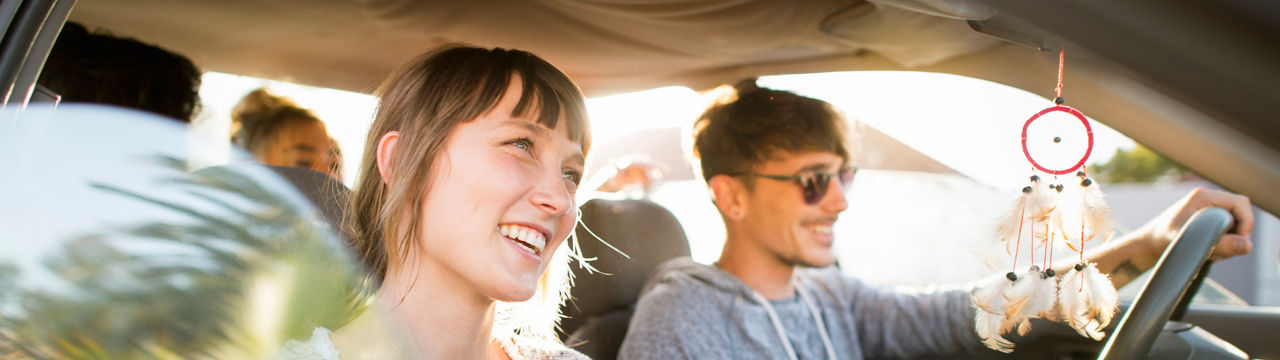 Smiling men and women traveling in car. Young friends are enjoying in road trip. They are wearing casuals during summer vacation.