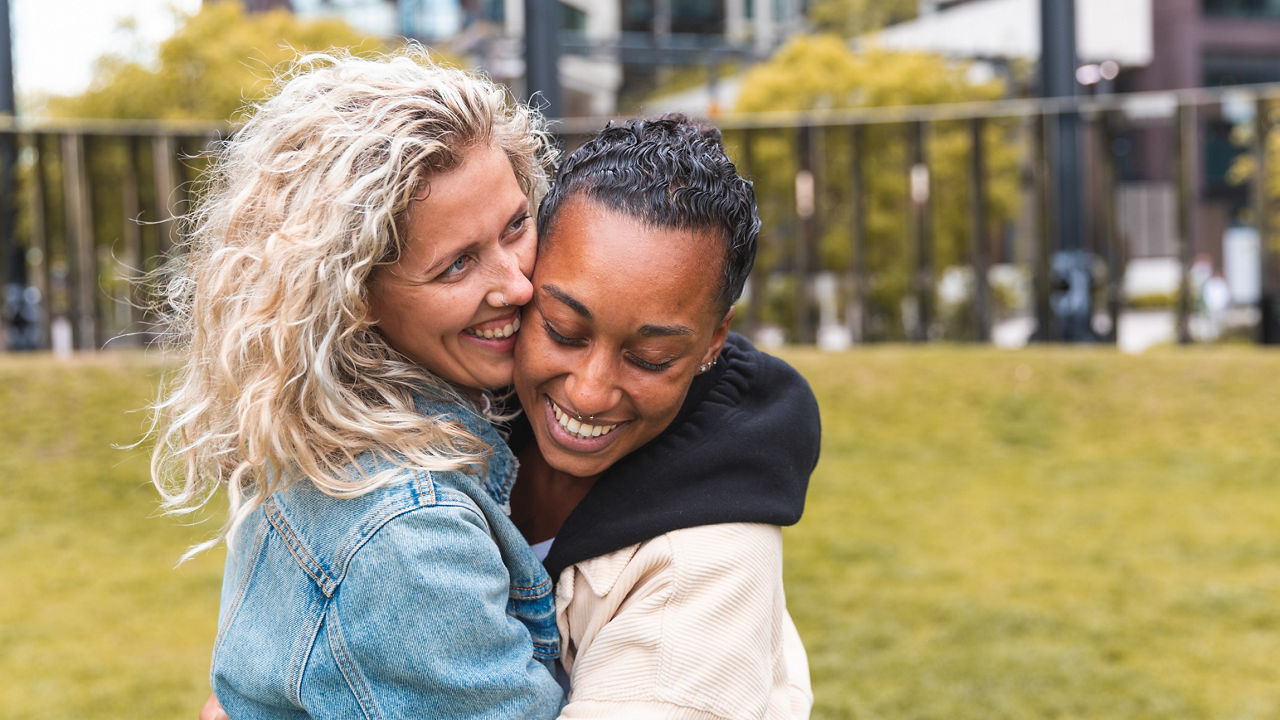 Happy multiracial girlfriends in love embracing and cuddling - Lesbian couple, millennials women, girls in London living happy lifestyle - LGBTQ concept with mixed race beautiful couple,