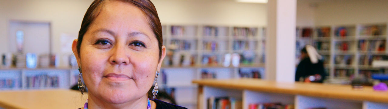 A portrait of an Indigenous Navajo high school teacher in a school library.