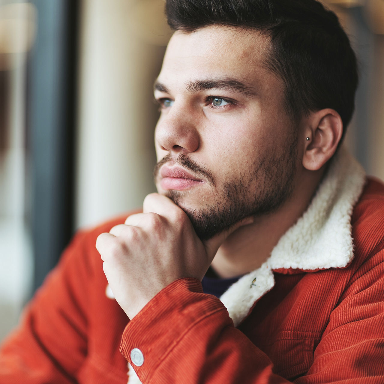 Portrait of pensive man looking through window.