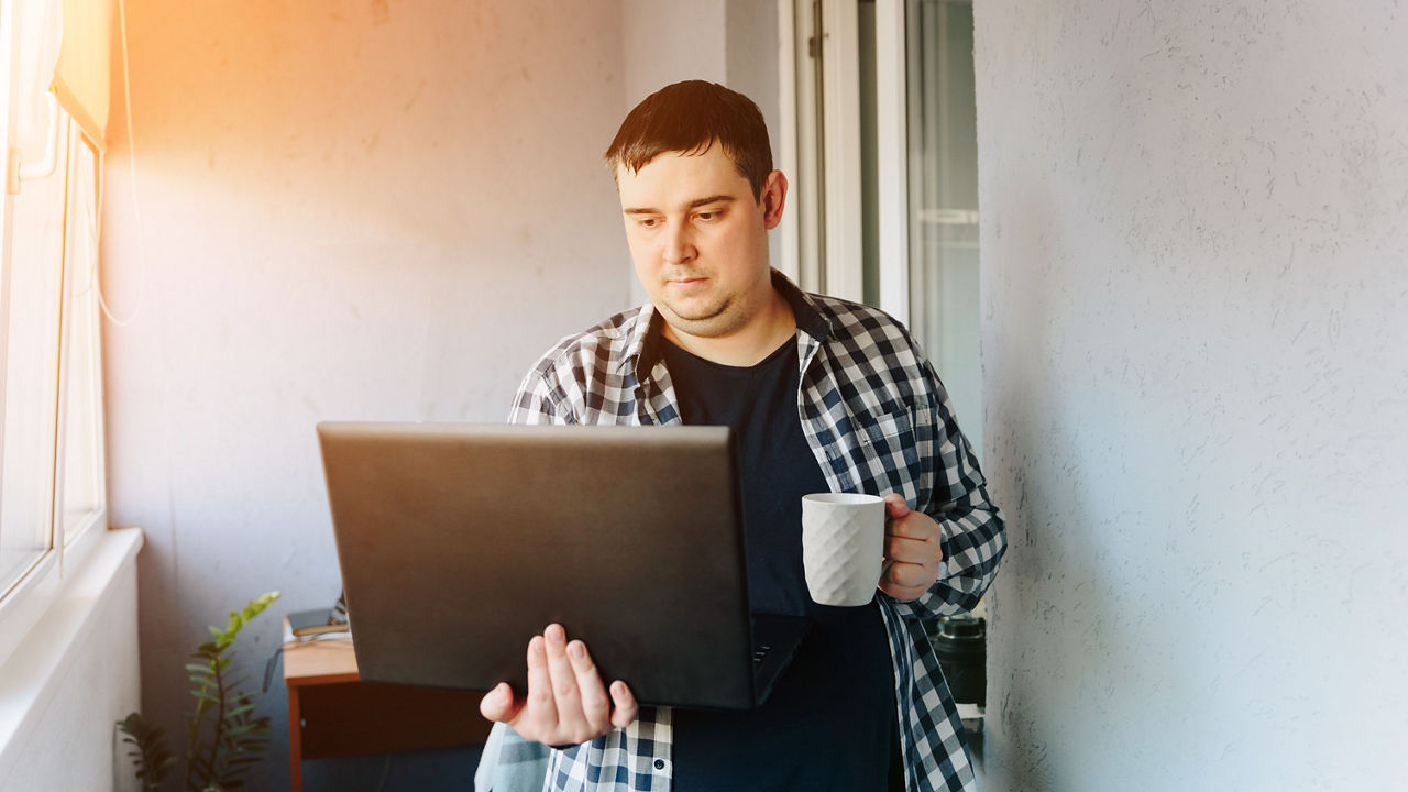 Man with laptop coffee cup in hand