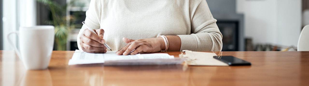 Cropped shot of a mature woman working through paperwork while sitting at home