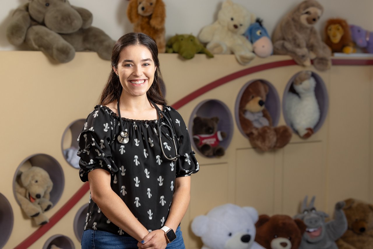 Angela smiling infront of a wall of teddy bears