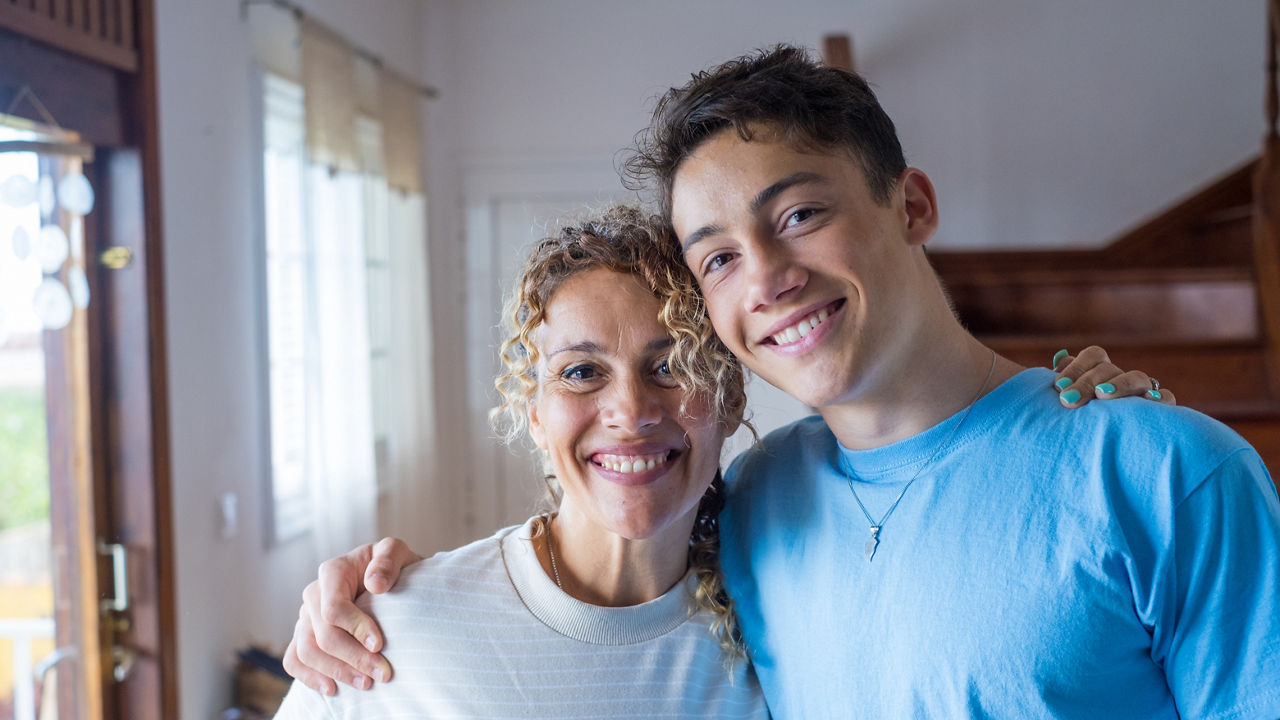 Portrait of grateful teenager man hug smiling middle-aged mother show love and care, thankful happy grown-up son in embrace cheerful mom, enjoy weekend family time at home together, bonding concept