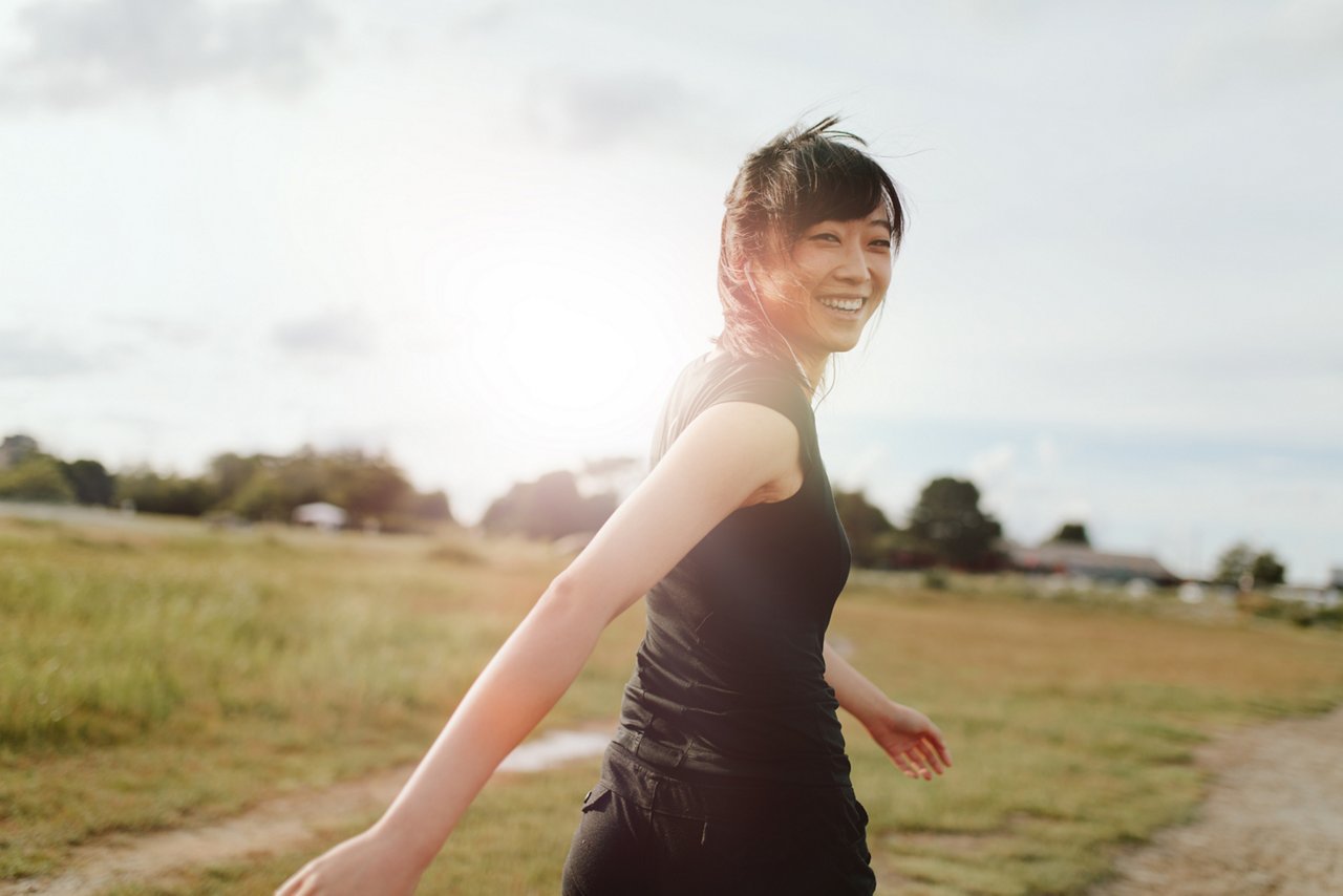 Outdoor shot of smiling young woman runner looking at camera.