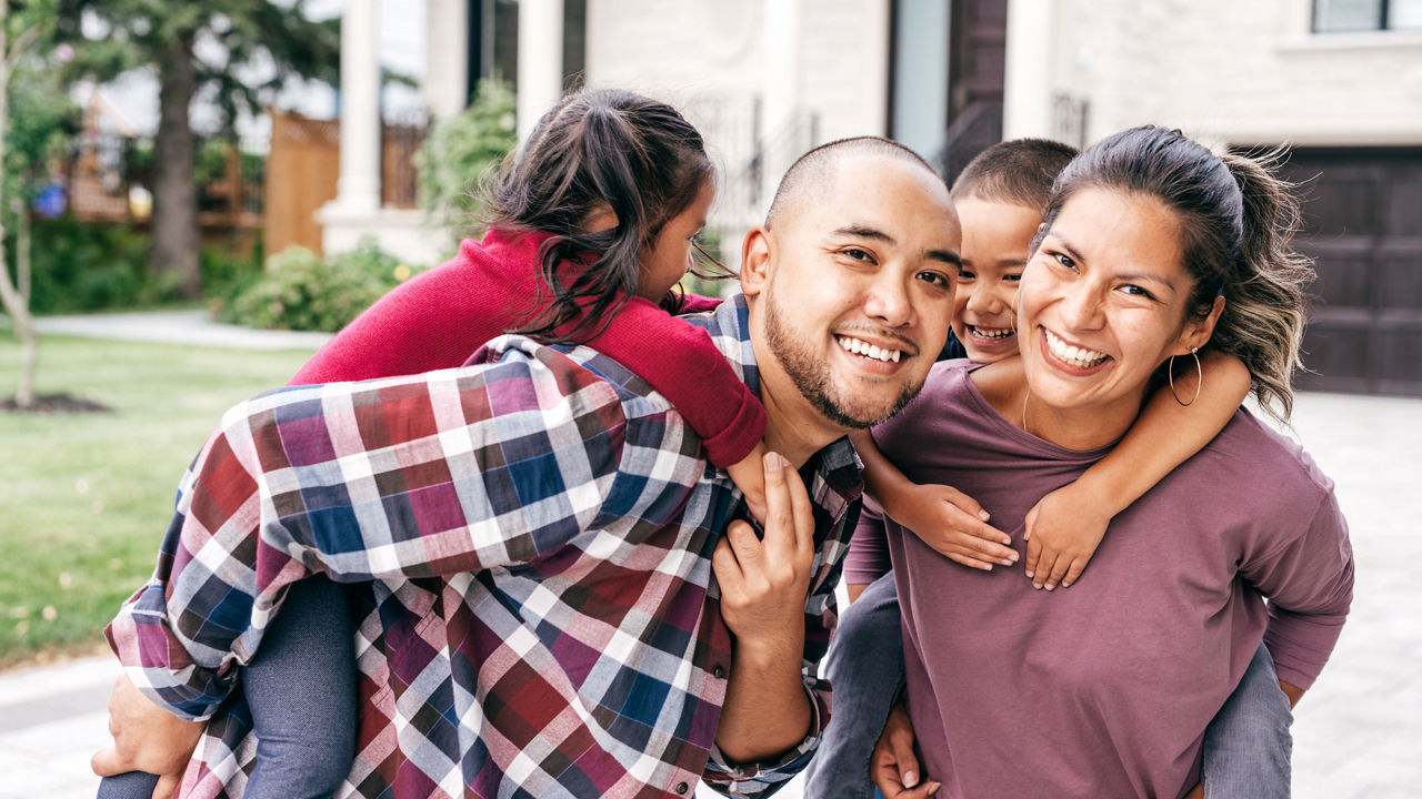 Parents carrying children piggyback outdoors