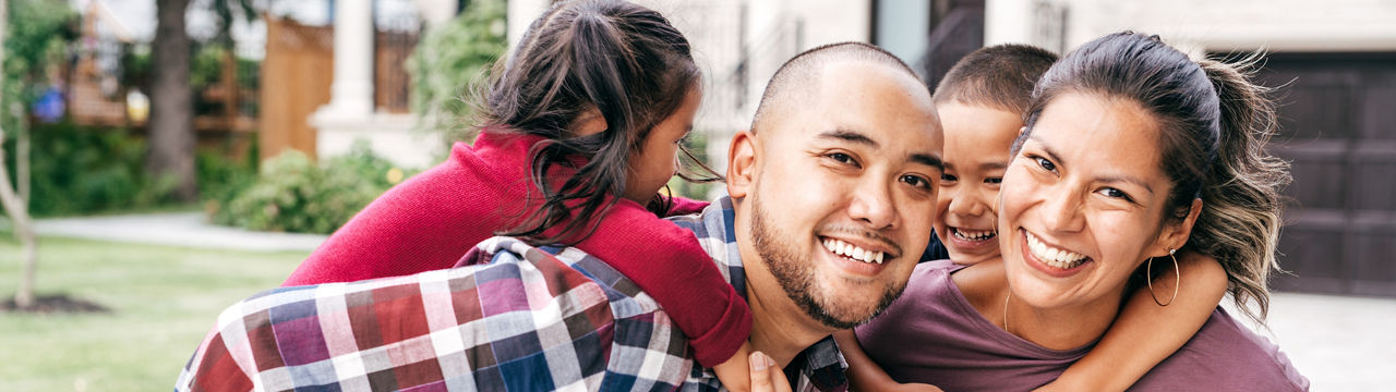 Parents carrying children piggyback outdoors