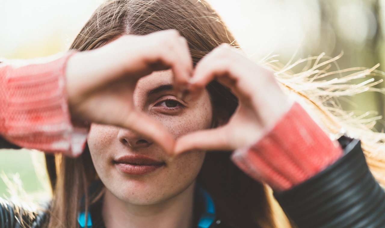 Portrait of beautiful girl making heart shaped symbol with hands