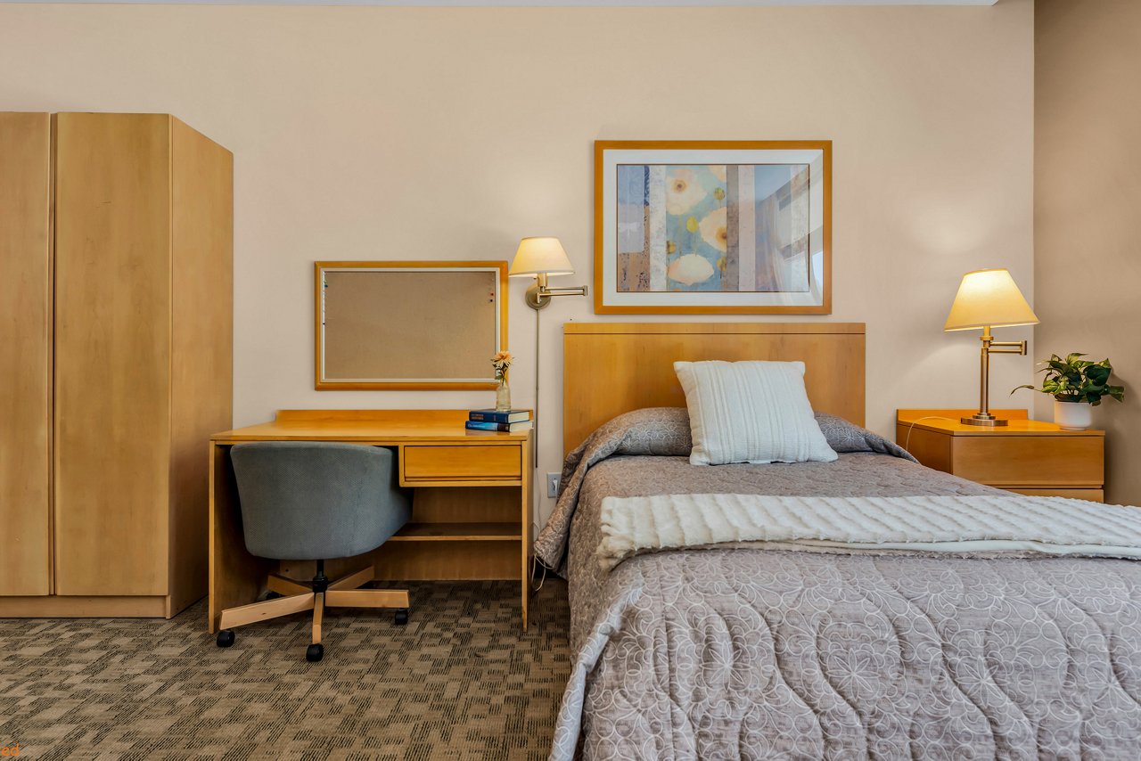 Inside a bedroom with a comfortable bed, a dresser and a small desk