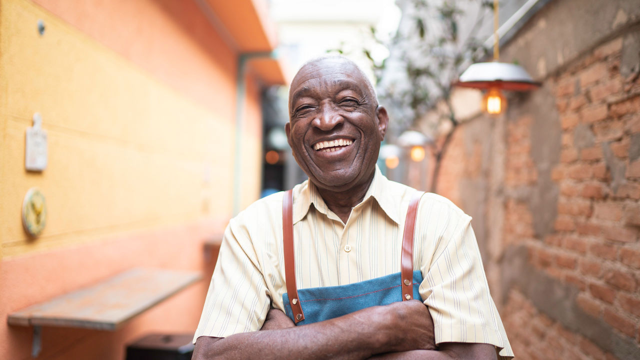 Portrait of smiling elderly waiter looking at camera