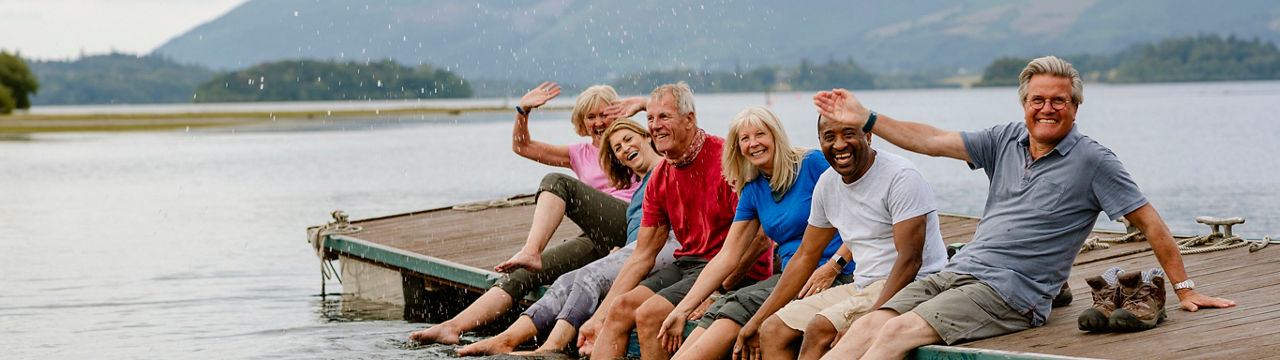 Group of mature men and women splashing on the jetty