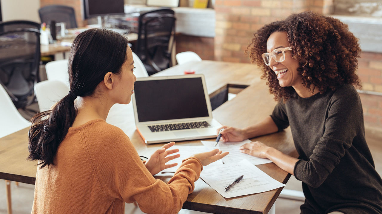 Two colleagues talking in office setting or meeting room