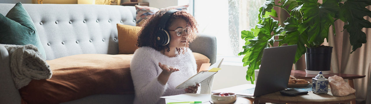 Shot of a young woman holding a notebook while making a video call on a laptop at home